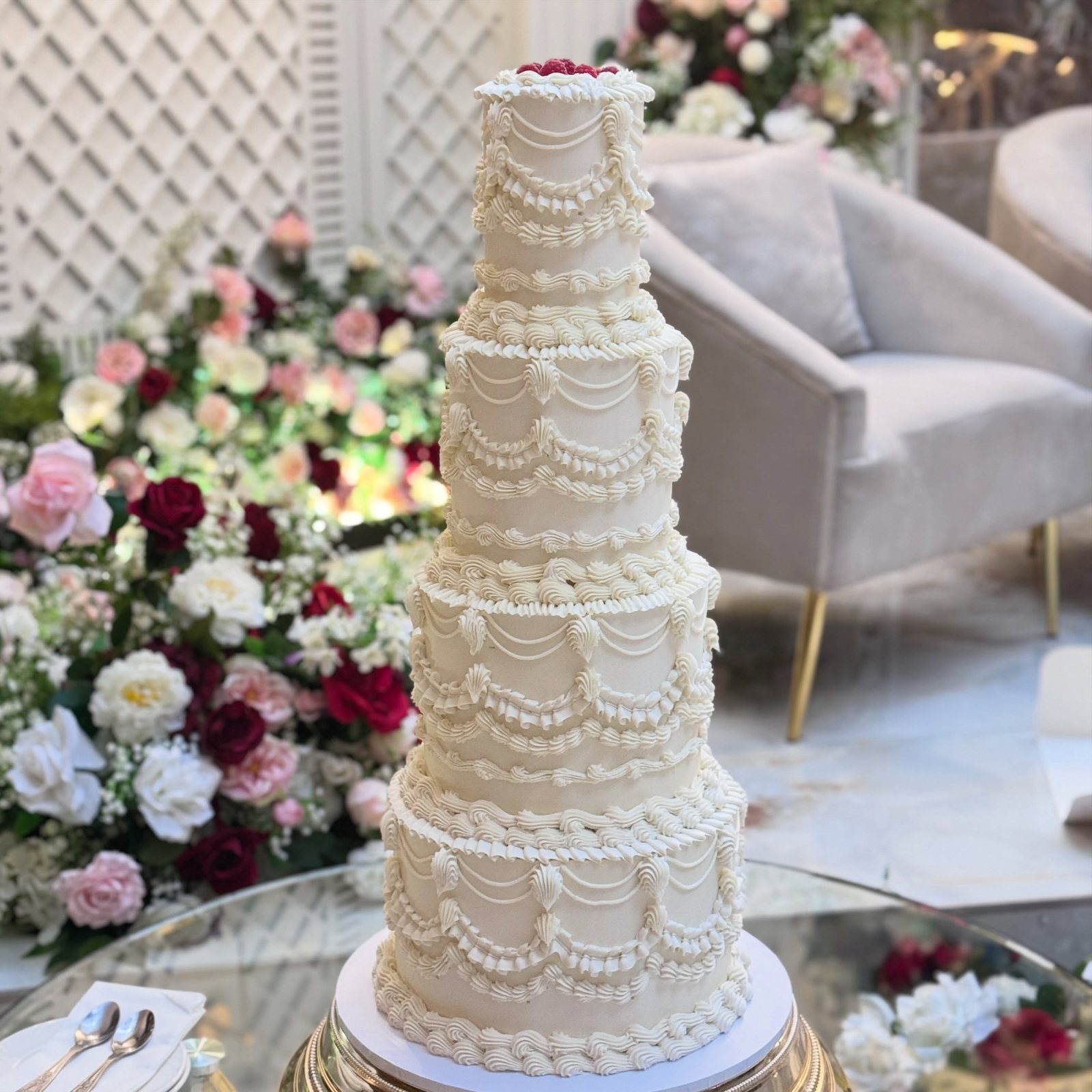 Tall white wedding cake with delicate piping in a floral venue
